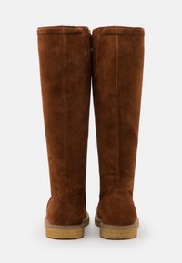 Brown suede knee-high boots with a smooth texture, side zipper closure, and round heel detail. Sturdy rubber outsole with a slight tread.