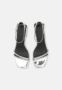 Sandali con tacco metallici argento, con punta quadrata, cinturino alla caviglia e due sottili fasce incrociate sul piede; texture liscia e design elegante.