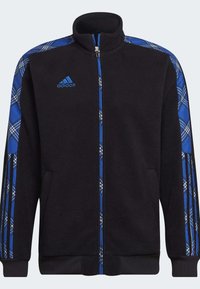 Schwarze Fleece-Jacke mit blauen Karomustern an den Ärmeln, Reißverschluss vorne und zwei Seitentaschen. Mit Adidas-Logo in Blau auf der Brust.