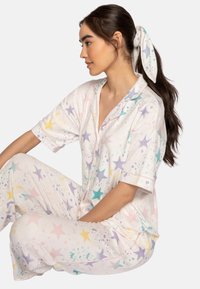 Short-sleeve, pastel-colored pajama set featuring a star pattern with splashes in yellow, purple, and teal. Soft, lightweight fabric with a relaxed fit.
