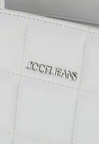 Borsa in pelle bianca con un design trapuntato, logo "JOOP!JEANS" in argento, cuciture curate e una texture liscia.