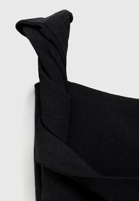 Bolsa de tela negra con diseño de asas retorcidas y textura suave, con refuerzos en la base para mayor durabilidad.
