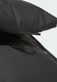 Black waterproof bag with smooth texture, featuring a top closure, a round leather accent, and a matte finish. Zipper details visible.