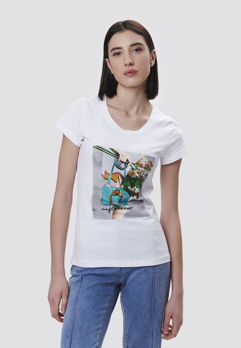 Camiseta blanca de algodón con un gráfico colorido de una mano sosteniendo una bolsa turquesa con flores, acompañada de la palabra "influencer".
