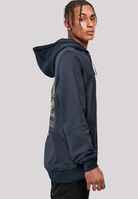 Navy blue hoodie with a front pocket, adjustable drawstring, and graphic design featuring yellow and gray elements on the back.
