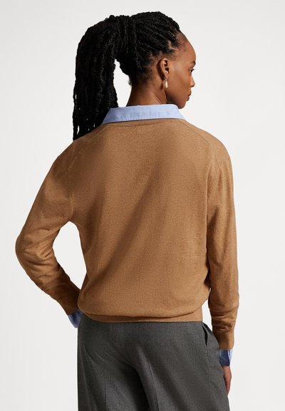 Καφέ πλεκτό πουλόβερ με άνετη εφαρμογή, μακριά μανίκια και μπλε πουκάμισο με γιακά από μέσα. Λεία υφή και ελάχιστες σχεδιαστικές λεπτομέρειες.