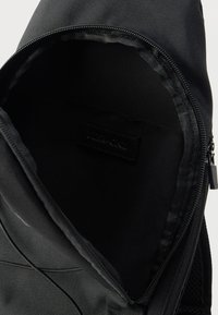 Εσωτερικό μαύρου υφασμάτινου σακιδίου με κλείσιμο με φερμουάρ· λεία υφή, επενδυμένο με μαύρο υλικό, με εσωτερική ετικέτα μάρκας.