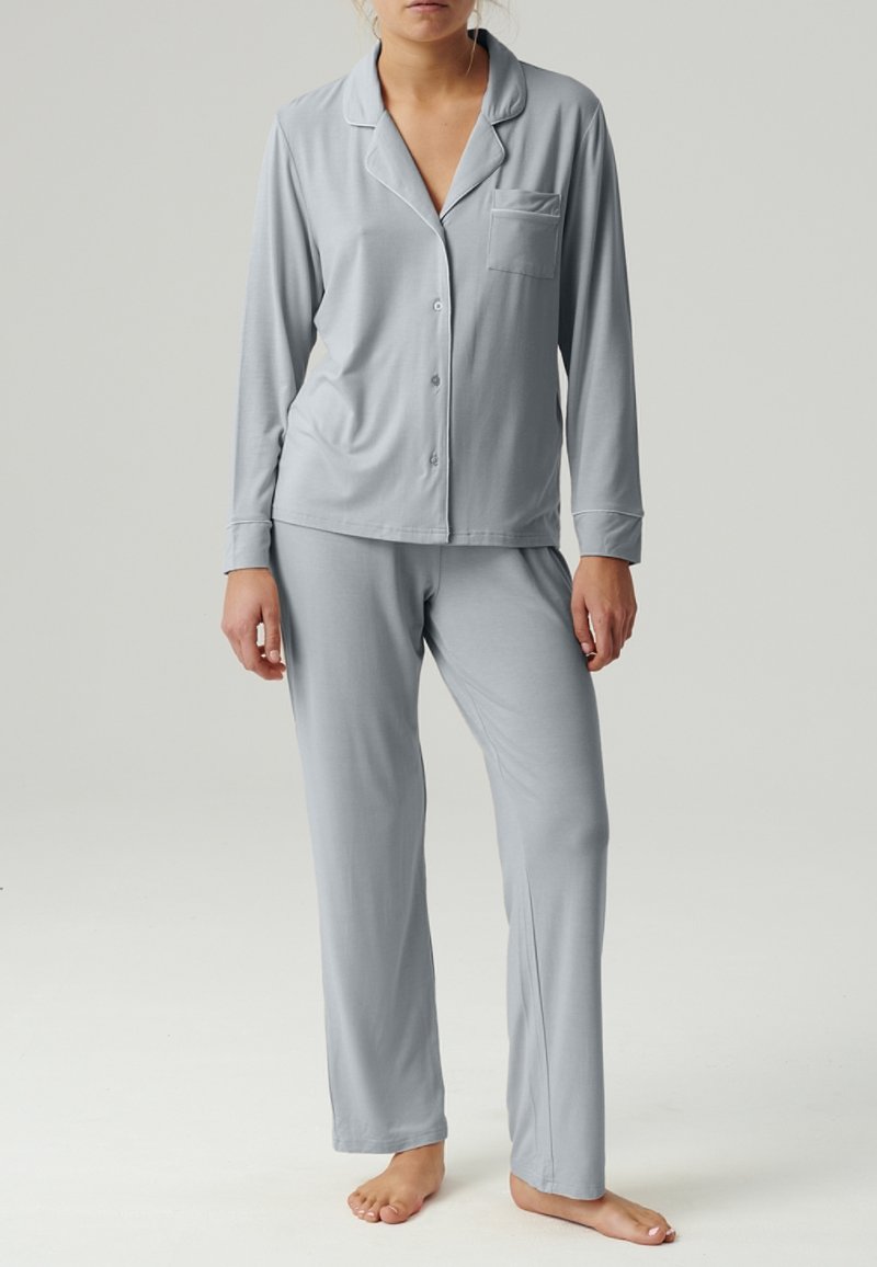 Jasnoszary zestaw piżamowy z długim rękawem, zapinany na guziki, z kieszenią oraz dopasowanymi spodniami o prostym kroju, wykonany z miękkiego materiału.