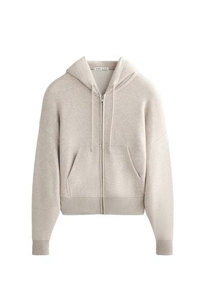 Svetlo siva zip-up kapuca iz mehkega materiala, ki ima sprednji žep, nastavljive vrvi in rebraste manšete ter rob.