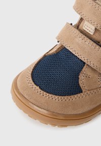 Schoenen met klittenbandsluiting, gemaakt van tan suede en met een marineblauwe mesh panel. Kenmerken zijn een gestructureerde rubberen zool en zichtbare stiksels.