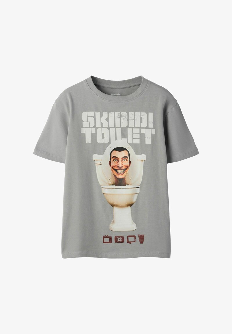 Γκρι κοντομάνικη μπλούζα με το κείμενο «SKIBIDI TOILET», ένα χαμογελαστό καρτούν κεφάλι μέσα σε λεκάνη τουαλέτας και τέσσερα μικρά καφέ εικονίδια από κάτω.