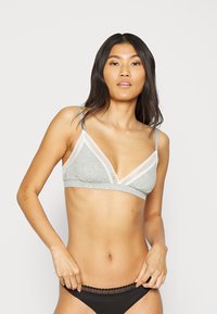 Bralet gri cu detalii din dantelă, având un design în formă de V, curele subțiri și ajustabile și o textură moale din bumbac. Purtați cu lenjerie intimă neagră.