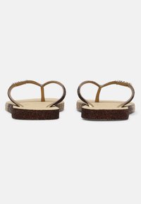 Căciuliță cu un design strălucitor de flip-flop-uri, cu o curea în formă de inimă, având tonuri de maron și auriu, și o talpă texturată pentru aderență.