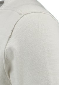 Maglione crema lavorato a maglia con scollatura rotonda e maniche corte. La texture è liscia, evidenziando dettagli di cucitura fine alle cuciture.