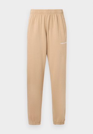 Béžové tepláky s elastickým pásom, zúženými nohavicami a bočnými vreckami. Na ľavom stehne sa nachádza malý biely text "PEGADOR".