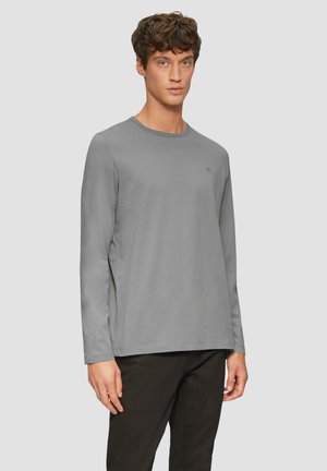 T-shirt à manches longues gris en tissu doux. Présente un col rond et un design minimaliste, avec un petit logo sur la poitrine.