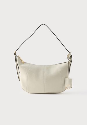 Witte schoudertas van leer met textuur, voorzien van een gebogen ritssluiting aan de bovenkant en een zwarte verstelbare riem, met een klein aangehecht zakje en details in goudkleur.