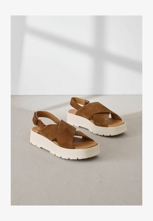 Barna nubuk platform szandálok keresztszalagos dizájnnal, bézs gumitalppal és állítható bokapántokkal. Texturált felsőrész sima talpbéléssel.