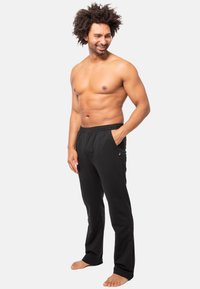 Zwarte sportbroek van zacht materiaal, met een elastische tailleband, zijzakken en een slank snit.