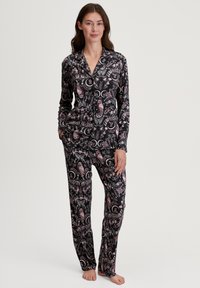 Langschedige, knoopsluiting pyjama set in het zwart met een roze uil en maan patroon. Zachte stof, slim-fit ontwerp, met een kraag.
