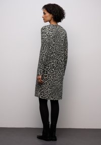 Cardigan lungo con stampa animalier grigia e morbida al tatto. Presenta maniche lunghe, una linea dritta e un collo rotondo, abbinato a stivaletti neri alla caviglia.