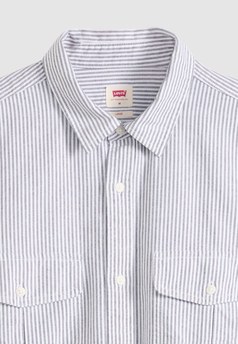 Chemise à rayures verticales blanches et grises avec col, boutonnée sur le devant, dotée de deux poches poitrine à boutons, étiquette Levi's taille moyenne, coupe ample.