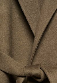 Manteau en laine marron clair avec col châle, design à rabat et ceinture nouée à la taille. Texture douce avec un détail de couture minimal.