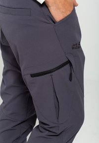 Grå utomhusbyxor med ett slätt, lättviktsmaterial. Har en sidofick med dragkedja och logodetalj. Skurna för komfort och rörlighet.