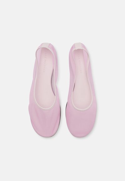 Lyserøde slip-on sko med en glat tekstur, der har en rund tå og en kontrasterende kant. Letvægtsdesign med en fleksibel sål.