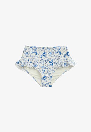 Femme portant un bikini blanc avec des motifs floraux bleus et des volants sur les bretelles et un bas taille haute.