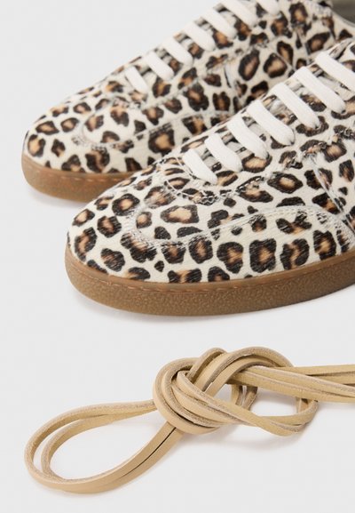 Sneakers i leopardmönster med beige läderstruktur, vita snören och sula i gummirubber. Inkluderar en knuten detalj i beige snöre.