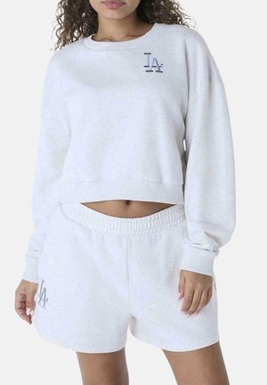 Sudadera blanca recortada con puños acanalados, que presenta un pequeño logo gris de "LA". Combinada con unos pantalones cortos a juego, de cintura elástica, también blancos.
