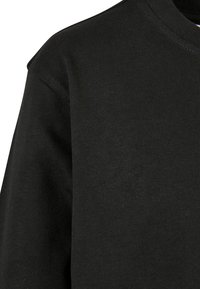 Zwarte lange mouwen shirt gemaakt van ribgebreide stof. Kenmerkt zich door een ronde halslijn en een simpele, gladde textuur zonder opvallende patronen.