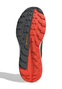 Semelle de chaussure présentant un design bicolore noir et rouge avec un motif texturé pour une meilleure accroche, marqué par un logo Continental proéminent.