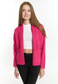Pink knitted cardigan with two front pockets, open design, long sleeves, textured fabric, and a relaxed fit. Worn over a white top.