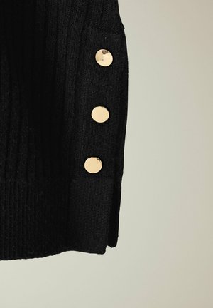 Maglione nero lavorato a maglia con una texture a costine e tre bottoni rotondi dorati sul lato. Il tessuto appare morbido e spesso.