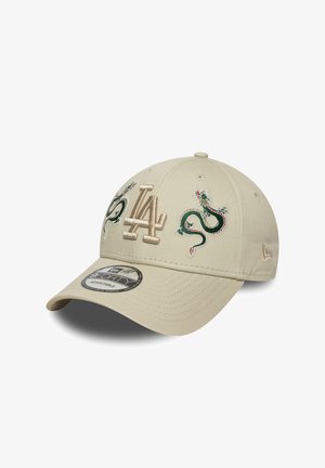 Beige cap with an adjustable strap, featuring embroidered green dragons and "LA" logo. Smooth fabric with a curved brim and vent holes.