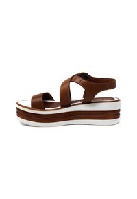 Sandalo con zeppa in pelle marrone, con punta aperta, cinturini incrociati e suola piattaforma bianca con strisce marroni. Chiusura con fibbia regolabile.