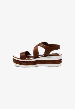 Sandalo con zeppa in pelle marrone, con punta aperta, cinturini incrociati e suola piattaforma bianca con strisce marroni. Chiusura con fibbia regolabile.