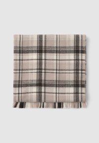 Koc w kratę w odcieniach kremowym, czarnym i delikatnym różowym. Posiada frędzle na brzegach oraz fakturę przypominającą wełnę. Kwadratowy kształt, idealny dla zapewnienia ciepła.