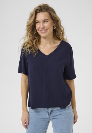 Chemise bleu marine à manches courtes en V, fabriquée dans un tissu lisse, dotée d'une coupe décontractée et d'un subtil détail de couture à l'avant.