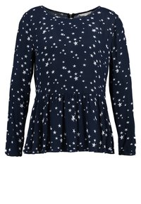 Maglietta a maniche lunghe di colore blu navy con motivo a stelle bianche, scollo tondo, vita arricciata e chiusura con zip sul retro. Tessuto morbido.