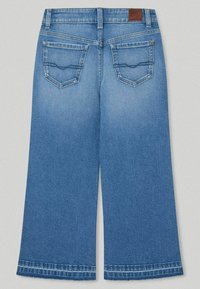 Džíny s širokými nohavicemi v světle modré barvě, které mají dvě zadní kapsy s prohnutým prošitím, koženou nášivku na pase a neupravené lemy.
