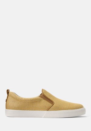 Beżowy, pleciony sneaker wsuwany z białą gumową podeszwą i brązowymi elastycznymi panelami po bokach na białym tle.