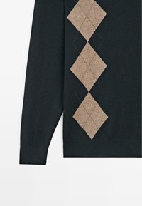 Donkergroen trui met een diagonaal patroon van lichtbruine ruiten. Zachte textuur met geribbelde boorden aan de mouwen en zoom.