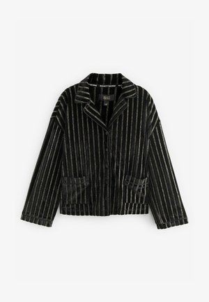 Mustmust värvi särk kuldsete vertikaalsete triipudega, sakiga krae ja nööbiga sulgemine. Omab kahte esipoolset taskut ja vabalt langevat lõiget.