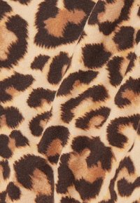 Textil s leopardím vzorem, který má béžové pozadí s tmavě hnědými a světlými tan skvrnami. Textura je hladká a elastická.