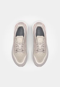 Vaaleanpunaiset urheilukengät, joissa on hengittävä verkko-osa, teksturoitu varvasosa, pastellisävyt ja paksu valkoinen pohja. "Pureboost" on näkyvillä sisäpuolella.