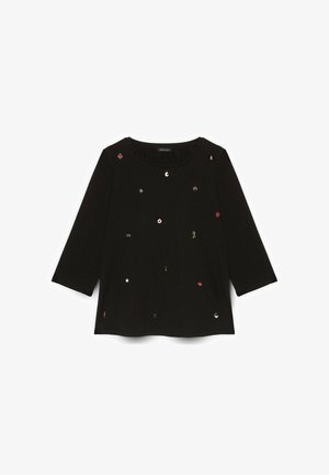 Maglietta nera a maniche lunghe realizzata in un morbido tessuto, con varie piccole decorazioni metalliche di forme e colori assortiti sulla parte anteriore.