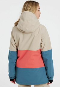 Farbig blockierte Jacke mit einem beigen oberen Bereich, einem korallenfarbenen Mittelteil und einem blauen unteren Abschnitt. Das Material ist glatt, die Jacke hat eine Kapuze und elastische Bündchen.